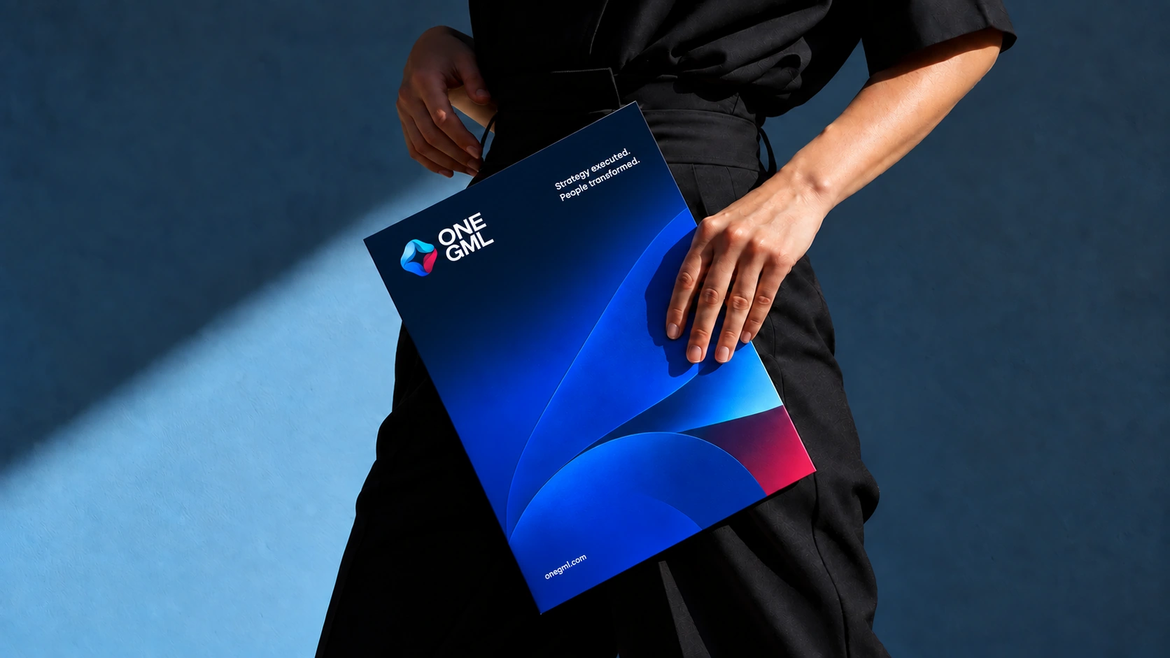 An executive holding a ONE GML folder with a brand-navy upper cover and a curved cobalt gradient following the ribbon form.